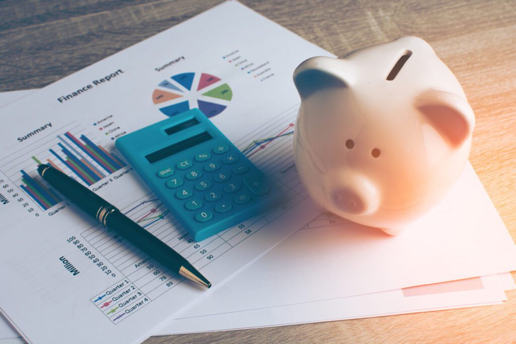 piggy bank and calculator lying on documents with finance reports for a mortgage and home loan